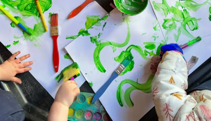 A table of children's paintings with paints and paintbrushes