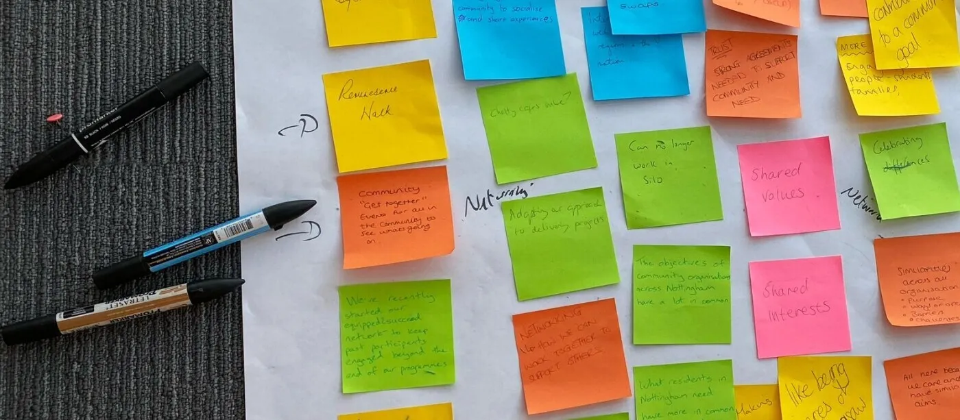 Different colour sticky notes on a large piece of paper and a few pens