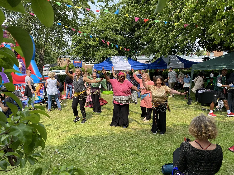 A group of people dancing outside in a park