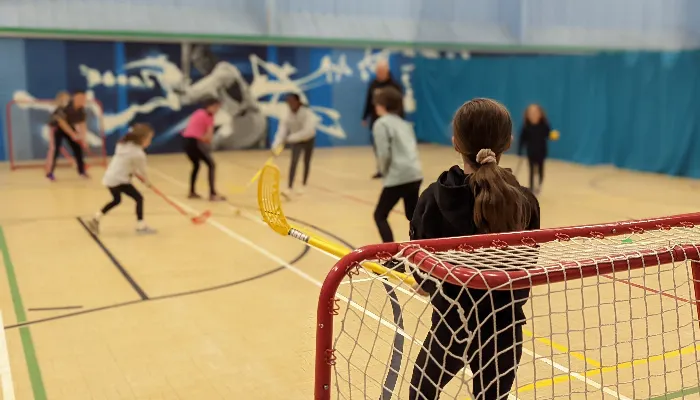 young people in a hall playing indoor hockey